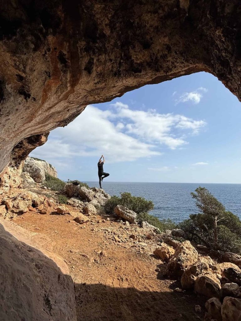 Cove Hike Mallorca coastal cave with hiker doing yoga, sea view and dramatic Mediterranean cliff scenery