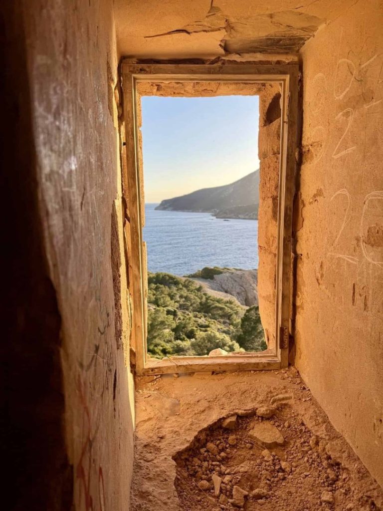 Elm Hike Mallorca: coastal view through rustic window with sea, cliffs and scenic Mediterranean landscape