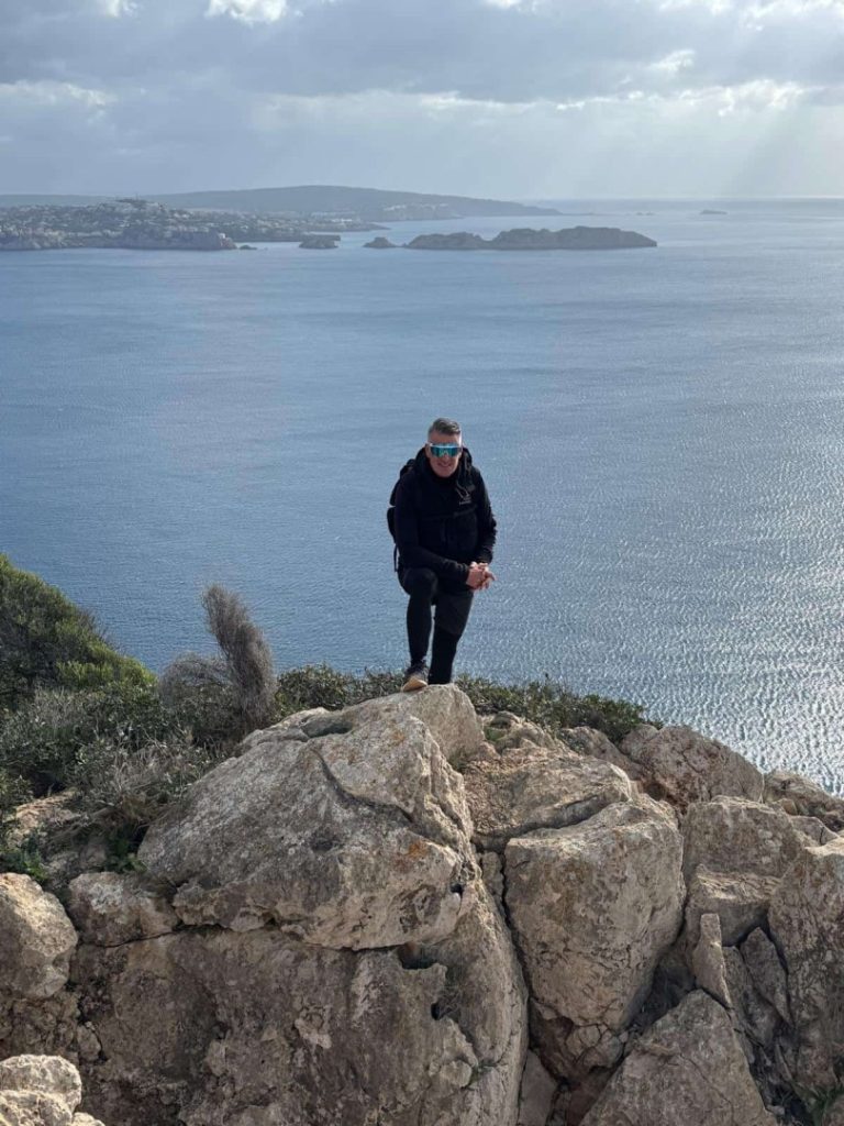 Monjo Hike Mallorca: hiker on rocky cliff with sea views, scenic coastline and panoramic Mediterranean landscape
