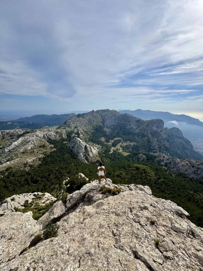 Ofra Hike Mallorca: hiker on mountain peak with panoramic views, rugged terrain and scenic Tramuntana landscape