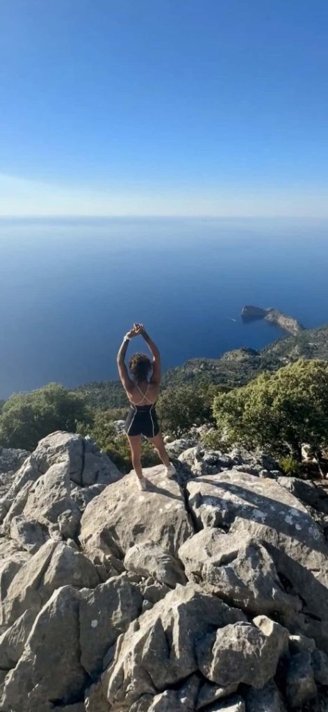 Steps Hike Mallorca: hiker on rocky peak with sea views, scenic coastal cliffs and panoramic Tramuntana landscape