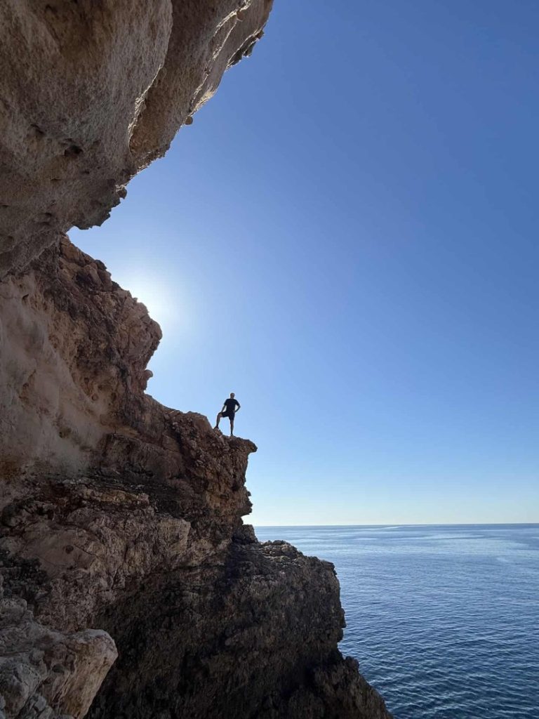 Toro Hike Mallorca: hiker on coastal cliff with open sea views, rugged rocks and dramatic Mediterranean landscape