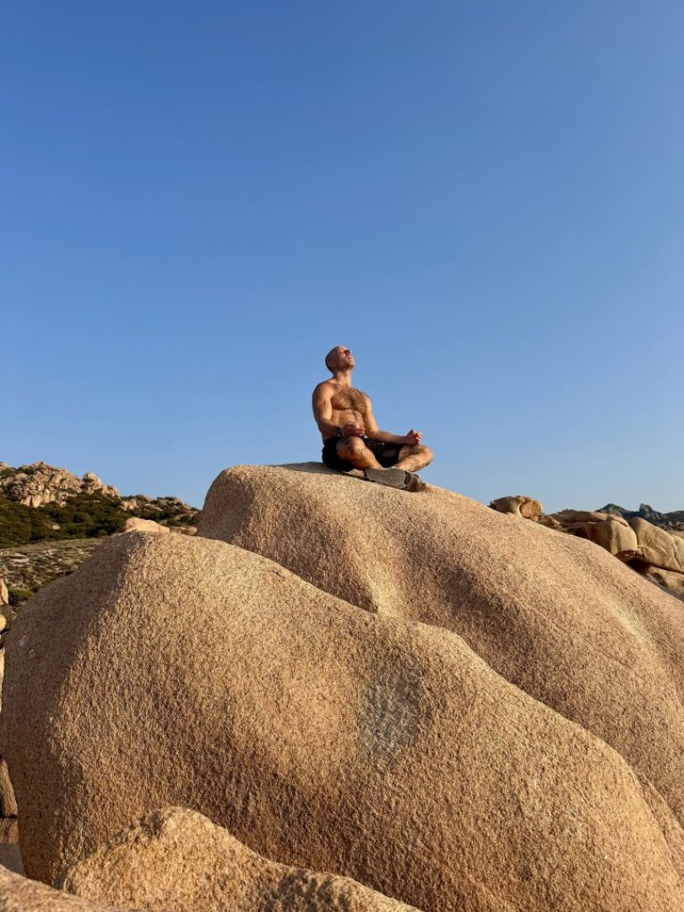 Coastal Hike Sardinia: Hiker meditating on rocky landscape with scenic coastal views and natural surroundings
