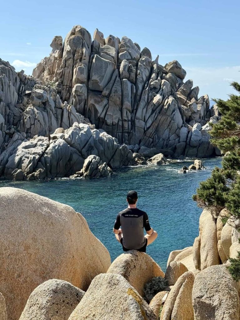 Lunar Hike Sardinia: hiker on rocks by crystal clear water with unique rock formations and scenic coastal landscape